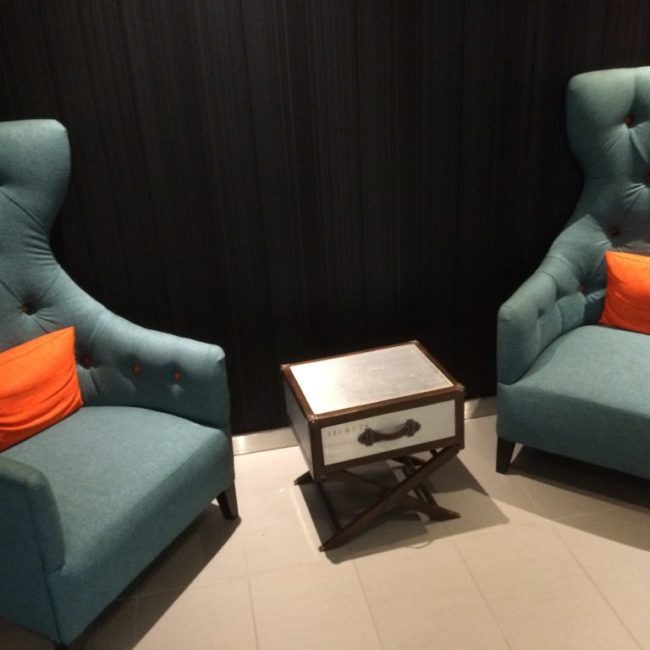 Two aqua chairs with orange pillows